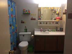 a bathroom with a toilet, sink and shower curtain is seen in this image taken from the doorway