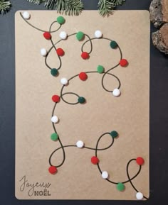 a christmas card made with yarn and pom - poms on top of a piece of paper