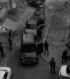 black and white photo of police officers standing near cars on the side of a road