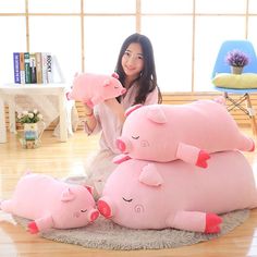 a woman sitting on the floor with three pink pig pillows in front of her face