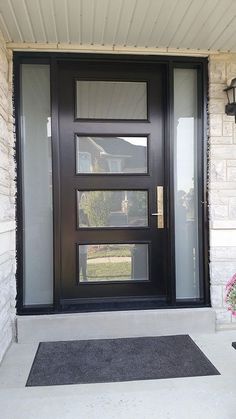 a black front door on a white brick house with flowers in the vase and lamp