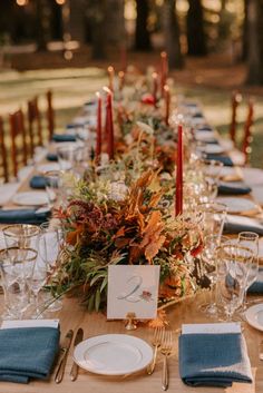 a long table set with place settings and candles for an autumn wedding reception at the park