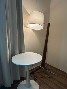 a white table lamp sitting on top of a wooden floor