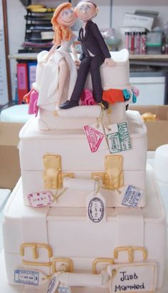 a wedding cake made to look like suitcases with people sitting on top of them