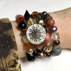 This Original Design Bracelet Was Created By Hand Using Vintage & Modern Elements Of Stone, Crystal, Stone, Faux Pearl, Shell And More In Tones Of Orange, Rust, Brown, Black, And White. Plain Pics Show The Flexible Continuous Revolutions Of Steel Wire. Note A: Silver Tone Metal Button, Balls Of Gold Stone & Yellow Jade (Pic1) Tibetan Agate Barrel, Picture Jasper Disc, Vintage Orange Oblong, Vintage Black/White Clay Pyramid, Sparkle Specialty Glass, Vintage Gold Tone Twist (Pic 3-5) Mixed Age Met Adjustable Silver Beads Fusion Jewelry, Adjustable Sterling Silver Beaded Fusion Bracelets, Adjustable Fusion Style Silver Beaded Jewelry, Adjustable Silver Beaded Fusion Bracelet, Fusion Style Beaded Bracelets For Jewelry Making, Silver Fusion Beaded Bangle Bracelets, Silver Fusion Bracelets Hand Wrapped, Silver Hand Wrapped Fusion Bracelets, Silver Beaded Bracelets With Unique Variations