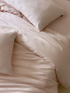 an unmade bed with pink sheets and pillows