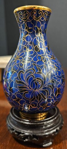 a blue and gold vase sitting on top of a wooden table next to a wall