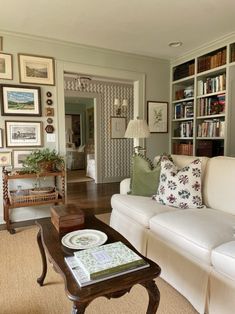 a living room filled with white furniture and lots of bookshelves on the wall