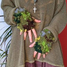 a woman is holding her hands in crocheted gloves with flowers and leaves on them