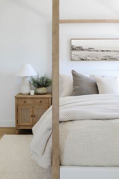 a bed with white linens and pillows in a bedroom next to a wooden night stand