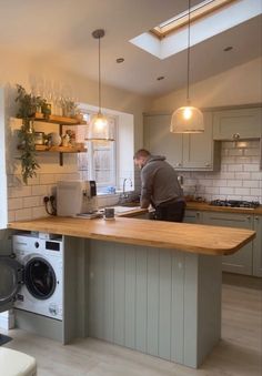 a man working in a kitchen next to a washer and dryer on the counter