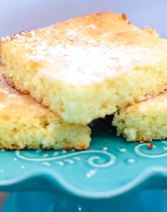 two pieces of cake sitting on top of a blue platter with powdered sugar