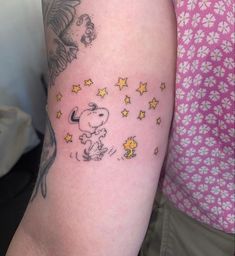 a person with a small tattoo on their arm that has stars and a cartoon character