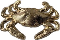 a gold colored crab brooch on a white background