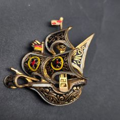 This vintage damascene ship brooch features a gold tone ship with black, red and yellow enamel details and measures 1.5" x 1.5" Collectible Gold Enamel Pins, Antique Gold Enamel Pin, Vintage Gold Enamel Lapel Pin, Victorian Gold Enamel Pin, Victorian Style Gold Enamel Pin, Antique Gold Enamel Brooches, Spain Vintage, Pirate Ship, Red And Yellow