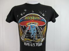 "Vintage 1970s black cotton rock and roll band concert tour t shirt with multi color glitter graphics. Front has a UFO and Boston 1979 U.S. Tour. Back has band members. Size small. Actual measurements are: 35\" around the chest 35\" around the waist 15\" shoulder seam to shoulder seam 27\" overall length In excellent condition." Retro Fan Merchandise T-shirt For Summer, Rock And Roll T-shirt With Band Logo For Summer, Spring Concert T-shirt With Graphic Design, Retro Black T-shirt For Concert, Fitted Graphic Design Top For Concert, Fitted Grunge T-shirt For Concerts, Vintage Spring Top For Concerts, Retro Festival T-shirt With Screen Print, Relaxed Fit T-shirt For Concerts And Music Festivals