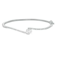 Turn heads with this eye-catching bangle bracelet. Fashioned in sterling silver, this stunning design showcases a 7.0 x 5.0mm oval-shaped lab-created shimmering white sapphire embraced by bypassing beaded ribbons. Petite diamonds lend further sparkle to the look. Radiant with 1/20 ct. t.w. of diamonds and a brilliant buffed lustre, this 7.0-inch bracelet secures with a tongue and groove clasp. Formal Oval Bangle With Diamond Accents, Oval Diamond White Bracelet With Diamond Accents, Modern Silver Oval Bangle, Modern Adjustable Oval Bangle, Classic Oval Cubic Zirconia Bracelets, Classic Oval Bangle With Diamond Accents, Oval Diamond White Bracelets In Fine Jewelry Style, Elegant Silver Oval Bangle, Oval White Bracelet Fine Jewelry