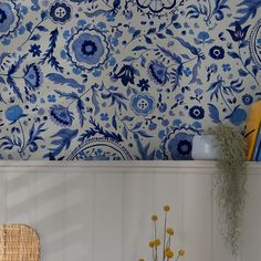 a blue and white floral wallpaper in a kitchen with yellow flowers on the shelf