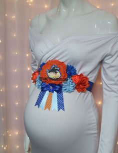 a pregnant woman wearing an orange and blue sash with flowers on it's waist