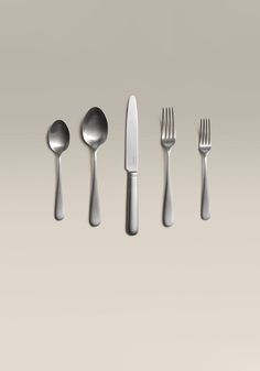 an assortment of utensils and spoons are arranged in a row on a gray background