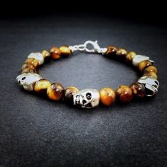 Silver Skull And Genuine Tiger’s Eye Beaded Bracelet Golden Brown Tiger’s Eye Gemstones Accent Silver Skulls In This Handmade Men’s Bracelet. Details: Bracelet Features 12x10mm Silver Plated Skulls And Individually Selected 8mm Genuine Tiger Eye Gemstones. Strung On Durable Stainless Steel And Secured With Lobster Clasp Closure. Measurements: 8 Inches In Length Including Clasp And 8mm At The Widest Point. (Also Available In 9” And 7”.) Weight: 31g Condition: Handmade Silver Metal Beaded Bracelets With 8mm Beads, Handmade Skull Bracelet As A Gift, Adjustable Silver Skull Beaded Bracelets, Silver Skull Beaded Bracelets As Gift, Adjustable Silver Beaded Skull Bracelets, Halloween Silver Jewelry With Round Beads, Silver Round Beads Jewelry For Halloween, Silver Jewelry With Round Beads For Halloween, Skull Shaped 8mm Bead Jewelry Gift