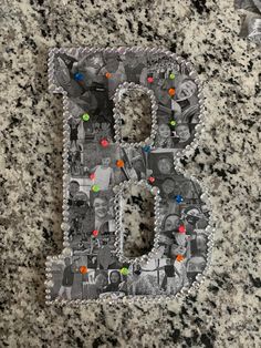 the letter b is made up of photos and beads on a granite surface with a toothbrush next to it