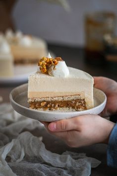 a person holding a plate with a piece of cake on it and whipped cream topping