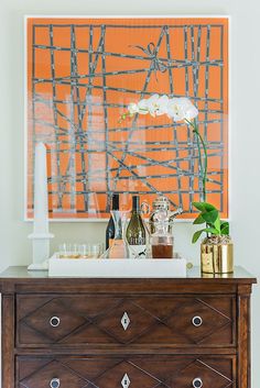 an image of a dresser with wine bottles on it and a painting in the background