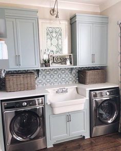 a washer and dryer in a laundry room with grey cabinets, white counter tops and gray flooring