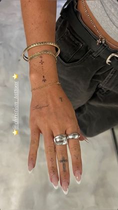 a woman's hand with tattoos and rings on her left wrist is shown in this image