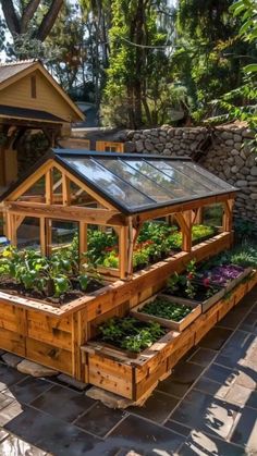 an outdoor garden area with raised wooden planters and plants growing in the ground next to a house