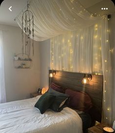 a bed that has some lights on the headboard and pillows in front of it