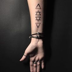 a woman's arm with three different tattoos on the wrist and one is holding her hand