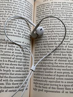 an open book with headphones attached to it's sides and earbuds in the middle