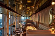 a long table with plates and silverware on it in front of a large window