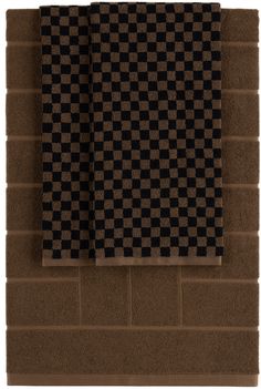 two black and brown checkered towels hanging on the wall next to a brick wall