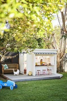 a child's play area in the backyard with toy cars on the grass and a bench