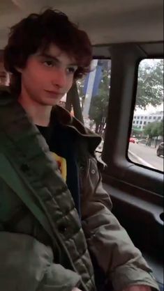 a young man sitting in the back seat of a car