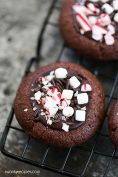 chocolate cookies with candy canes and marshmallows are cooling on a wire rack