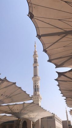 a large white building with a clock on it's side and many umbrellas over it