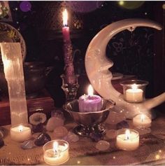 candles are lit in front of a crescent shaped candle holder on a table with other items