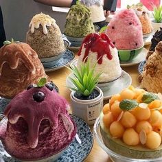 a table topped with lots of different types of ice creams and desserts next to a window