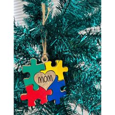 a christmas tree ornament with puzzle pieces and the word mom hanging from it