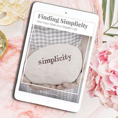 a tablet sitting on top of a table next to pink flowers and other items with the words, finding simplicity