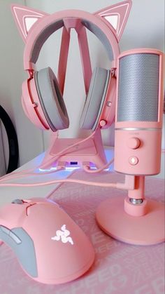 a pink computer mouse and headphones sitting on a desk next to a cat shaped microphone