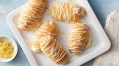 a white plate topped with pastries next to a bowl of lemon zest