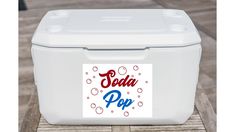 a cooler sitting on top of a wooden table with soda pop sticker on it