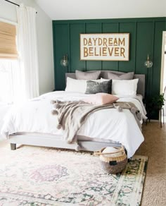 a bedroom with green paneling and white bedding, rugs and pillows on the floor