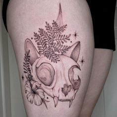 a woman's thigh with a cat skull and flowers on it