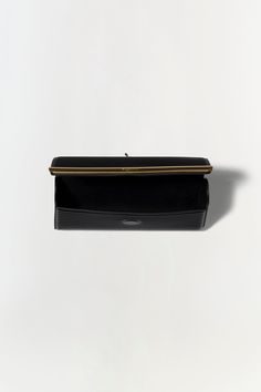 PRE-FALL 2024 WOMEN'S COLLECTION The Rolo Clutch in Black. This sleek bag features a streamlined design accentuated by a chic gold accent stripe. Its minimalistic elegance is perfect for any formal occasion. The long, delicate chain allows for versatile wear, letting you carry it as a shoulder bag or tuck the chain inside for a classic hand-held look. Modern Office Clutch With Rectangular Case, Modern Rectangular Case Clutch For Office, Modern Rectangular Office Clutch, Chic Rectangular Clutch For Office, Modern Structured Clutch For Formal Occasions, Chic Black Clutch With Rectangular Case, Black Rectangular Clutch For Formal Occasions, Modern Business Clutch With Gold-tone Hardware, Chic Black Rectangular Clutch